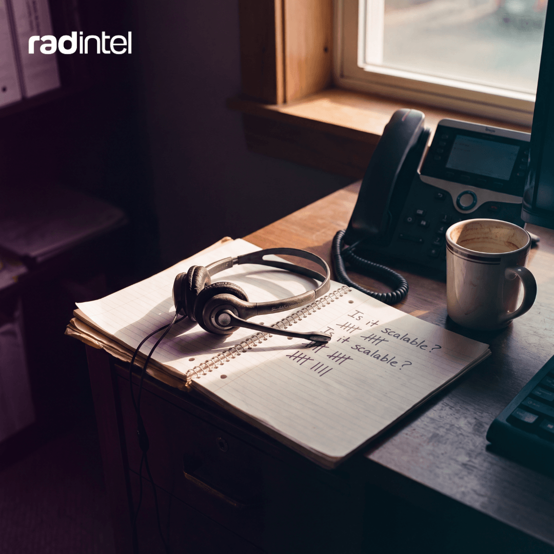Headset resting on an open notebook beside an office phone and coffee cup, representing insights gathered from sales calls.