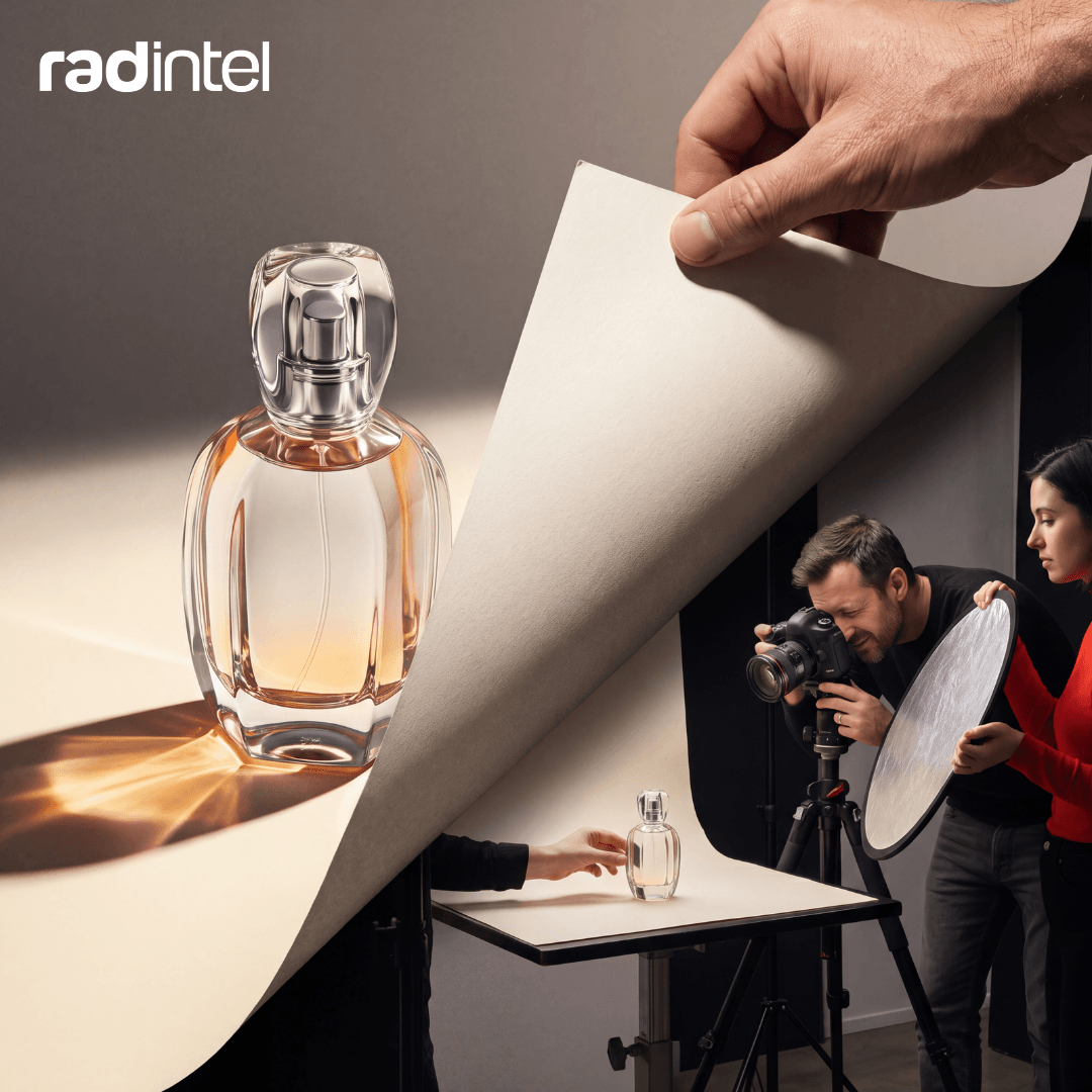 A hand peels back a polished perfume ad to reveal the photo shoot behind it, where a photographer, an assistant holding a reflector, and a stylist positioning the bottle are at work.