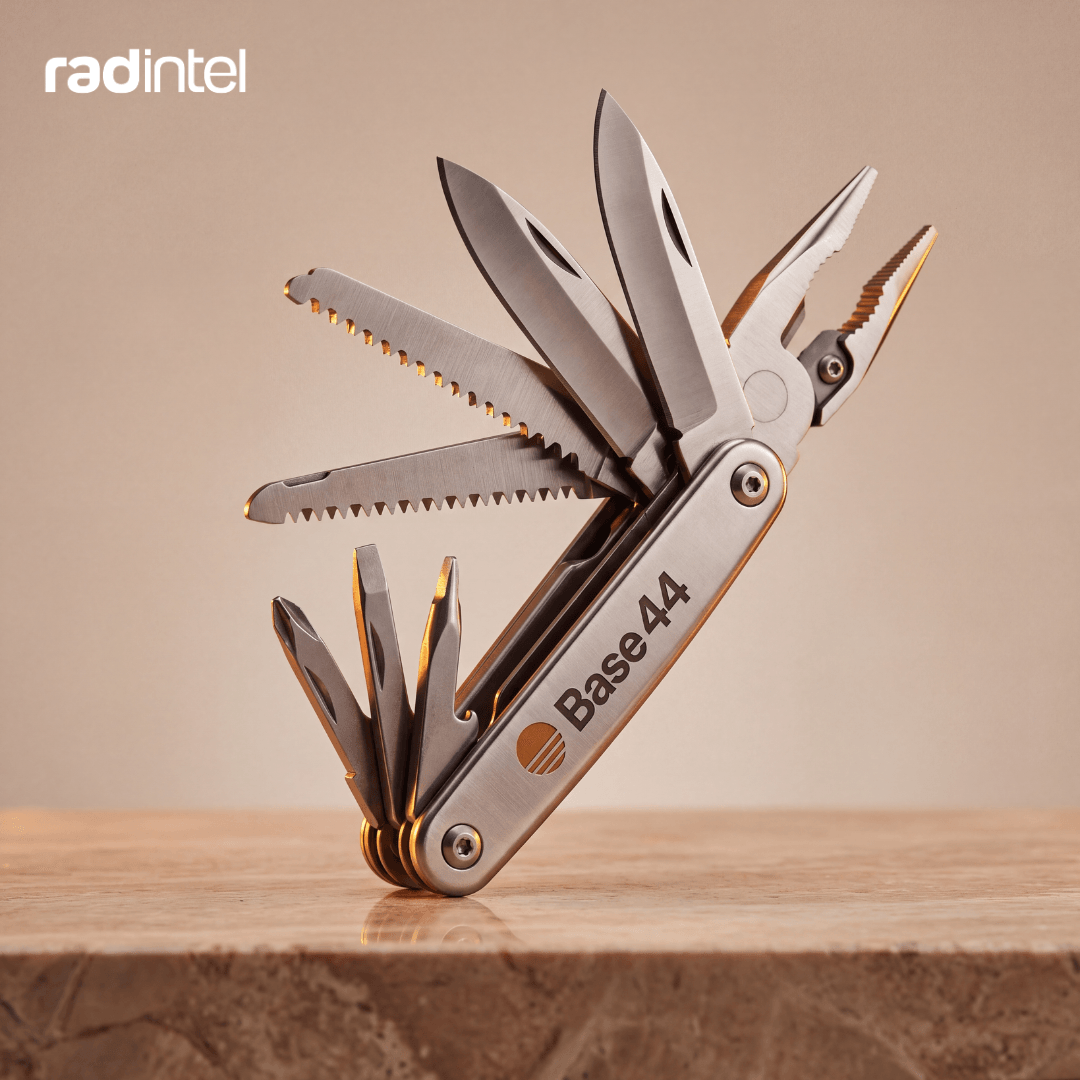 A Base44-branded stainless steel multitool open on a black surface, its various blades and tools fanned out.